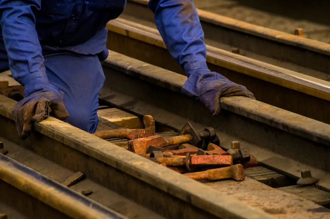 Mains gantées d'un ouvrier ferroviaire au travail sur des rails avec ses outils, formation pratique SECUFER